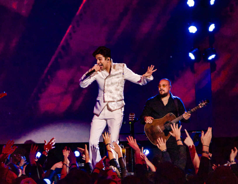 Luan Santana em performance energética durante a turnê 'Ao Vivo na Lua', cantando para um público animado em um show marcante com muita interação e música ao vivo.