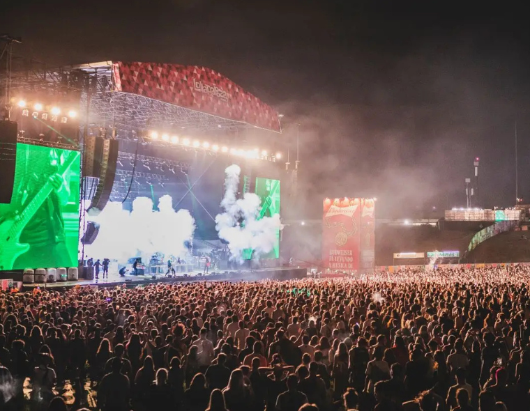 Grande público assistindo a show noturno no palco principal do Lollapalooza Brasil, com luzes, fumaça e som ao vivo no Autódromo de Interlagos.