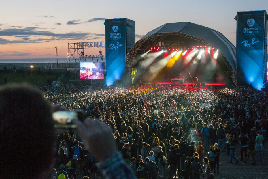 Multidão assistindo ao show no palco principal do Primavera Sound 2014 ao pôr do sol, com luzes coloridas e telões de apoio.
